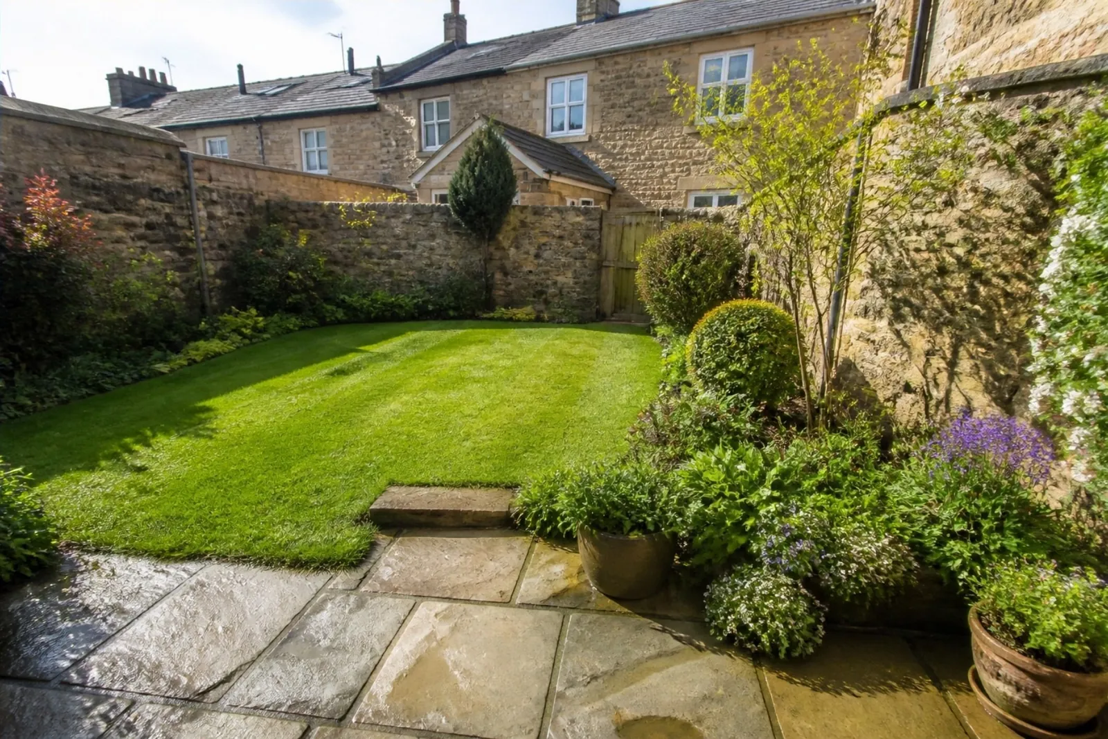 Stone cottage back garden in a market town with a new lawn, old stone walls and a flagged terrace